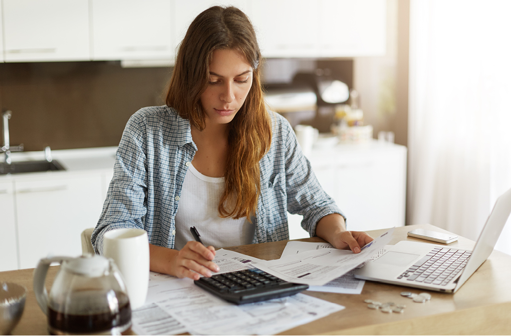 Woman looking down at paperwork with calculator