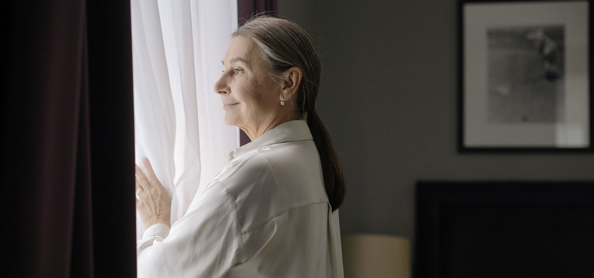 Older woman looking outside window