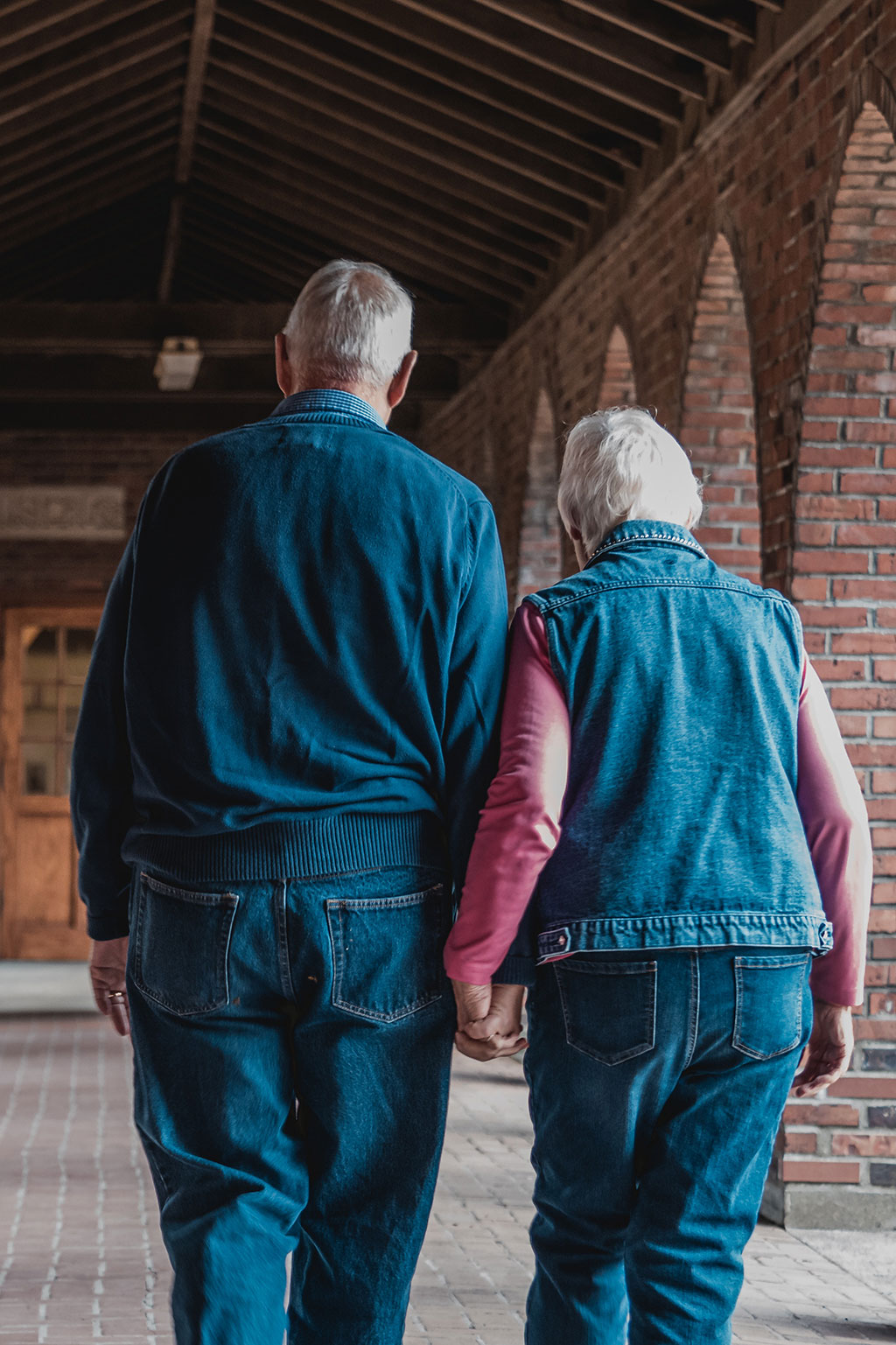 Older couple holding hands walking away from camera