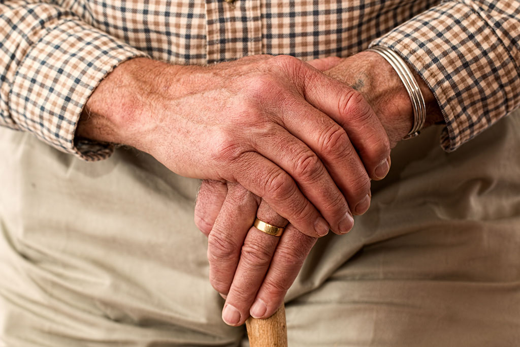 Older mans hands crossed over cane