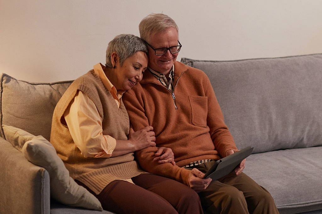 Older couple sitting on couch looking at tablet