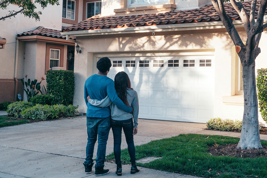 Couple in driveway looking at home