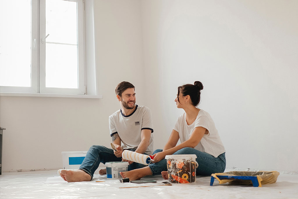 Couple sitting on floor about to paint bedroom walls