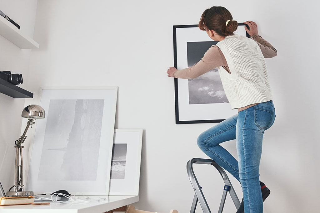 Woman hanging up art of wall