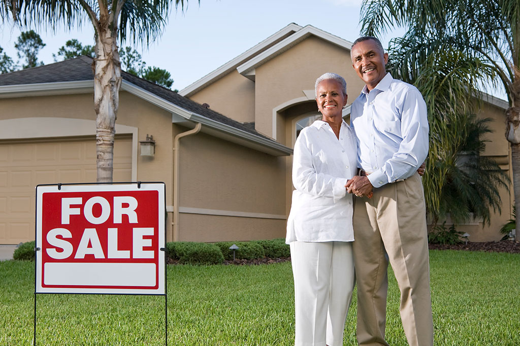 Older couple standing in front of house for sale