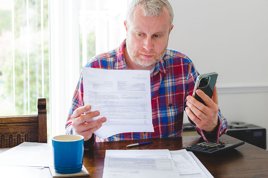 Man looking at bills in hand about to make a call