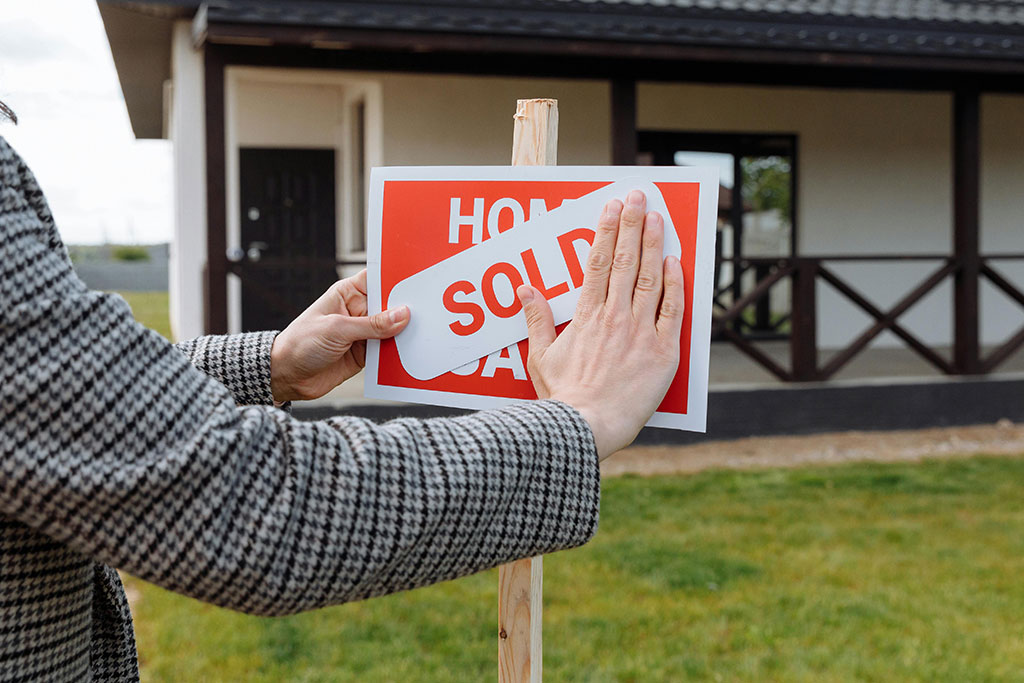 House for Sale sign bring covered up with sold sign