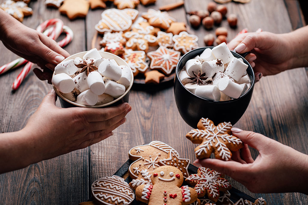 Two cups of hot chocolate and cookies on table