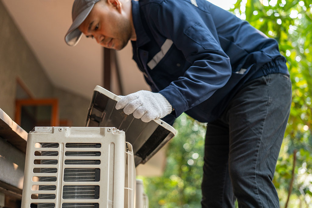 Man inspecting condenser unit outside