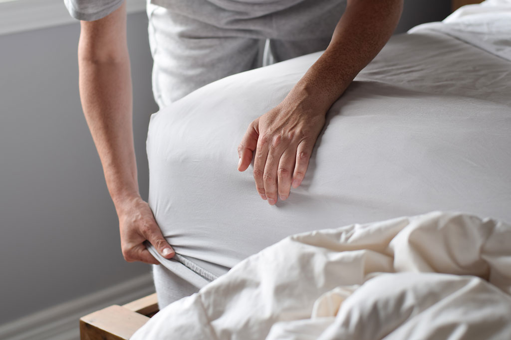 Person changing sheets on bed