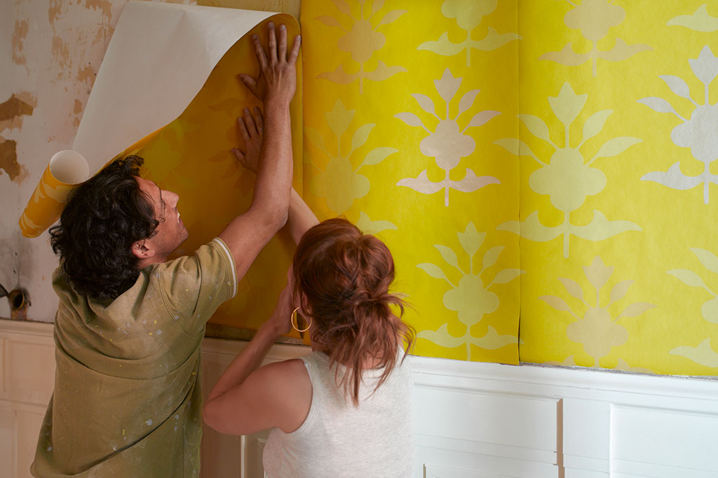 Couple putting up wallpaper