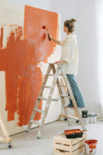 Women painting walls of house