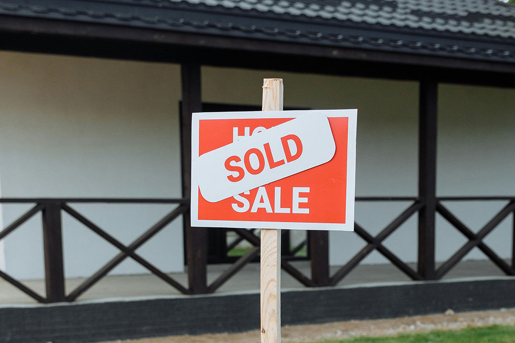 Home for sale sign with sold sign on top outside of home