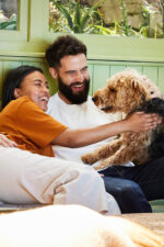 Couple petting dog on couch
