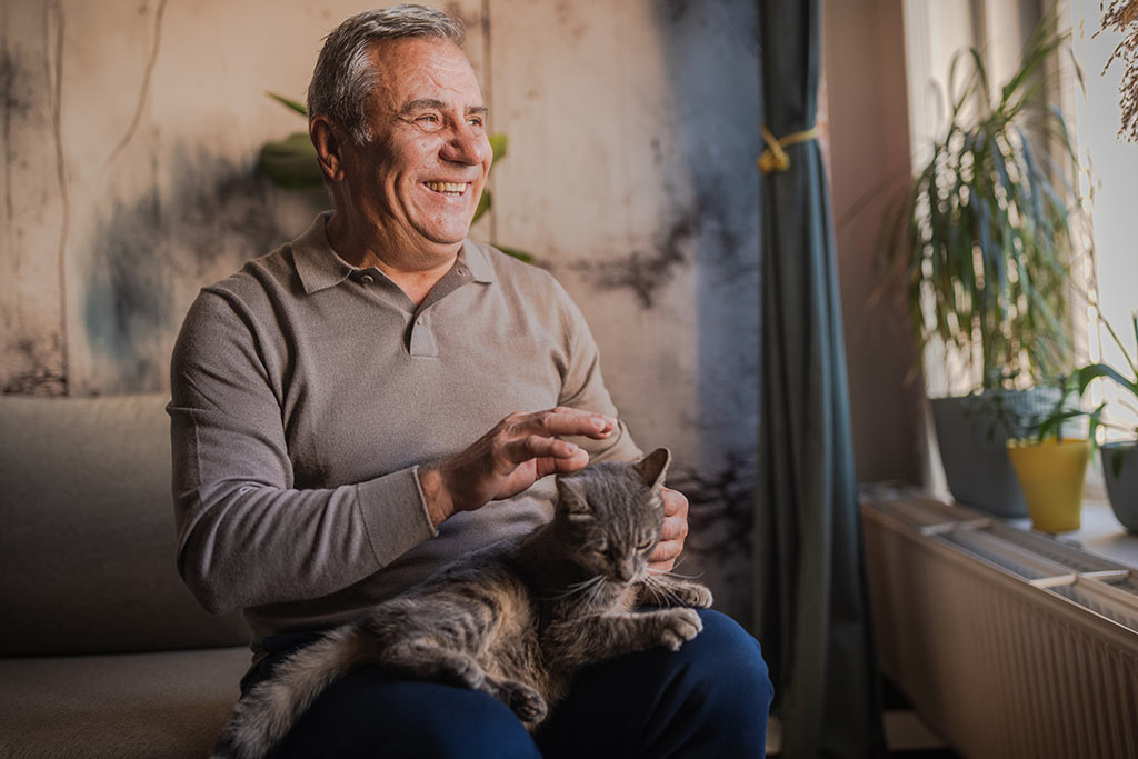 Older man sitting down with cat in lap