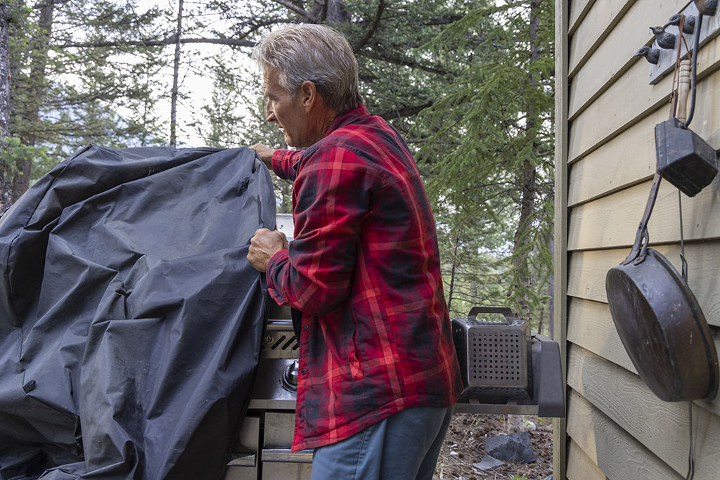 Man covering grill with cover